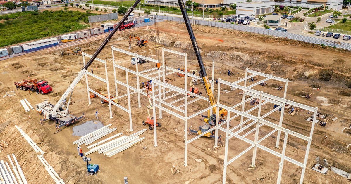 Công trường dựng khung thép nhà xưởng với cần cẩu và máy móc thi công