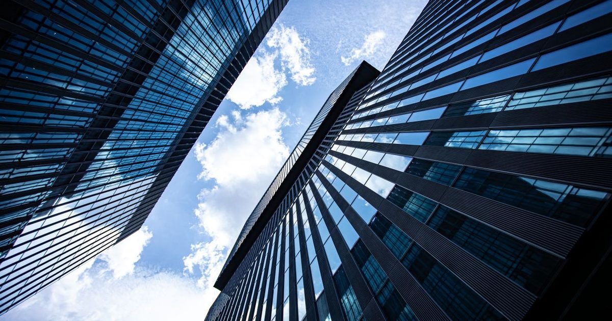 2026 Update: Listing and Trading Registration Rules 1 Các tòa nhà văn phòng mặt kính cao tầng nhìn từ dưới lên dưới bầu trời xanh
