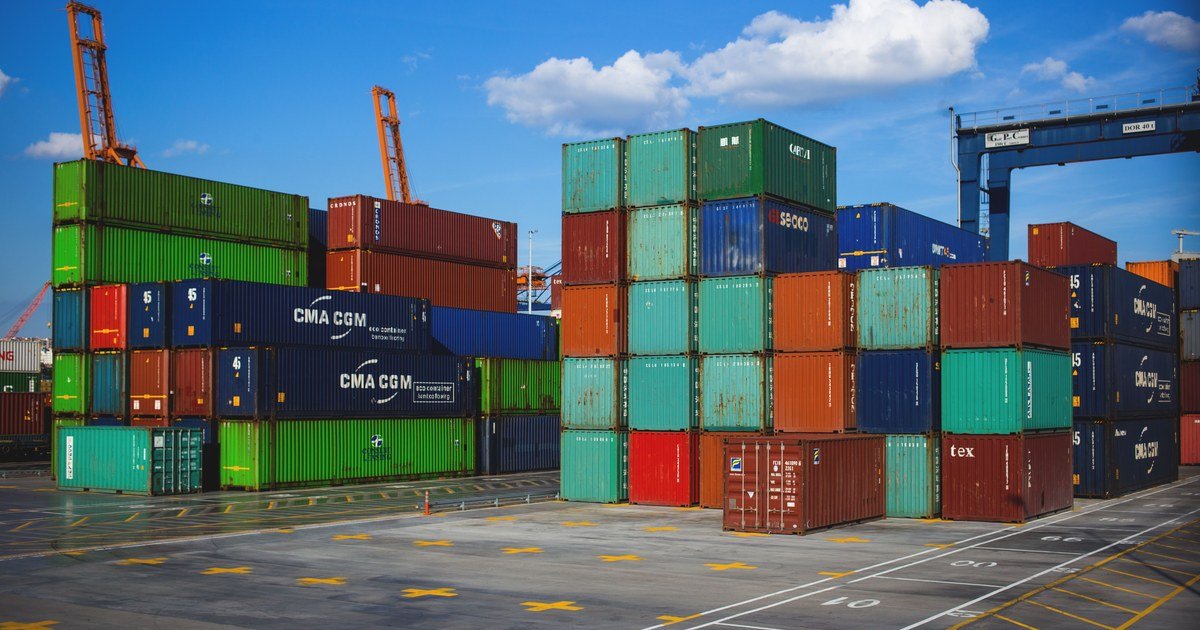 Import-Export Tax Guide for EPEs 1 Container hàng hóa nhiều màu xếp chồng cao tại cảng biển dưới bầu trời xanh