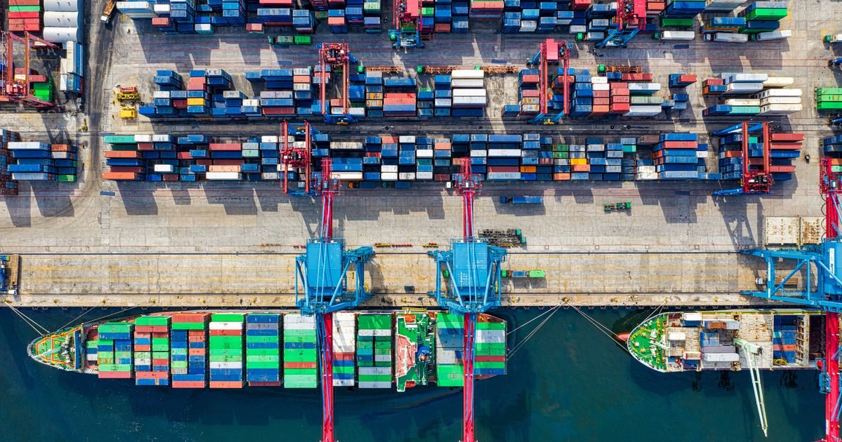 Tax for Logistics and International Transport 1 Cảng container nhìn từ trên cao với tàu hàng đang xếp dỡ, minh họa lĩnh vực logistics và vận tải quốc tế