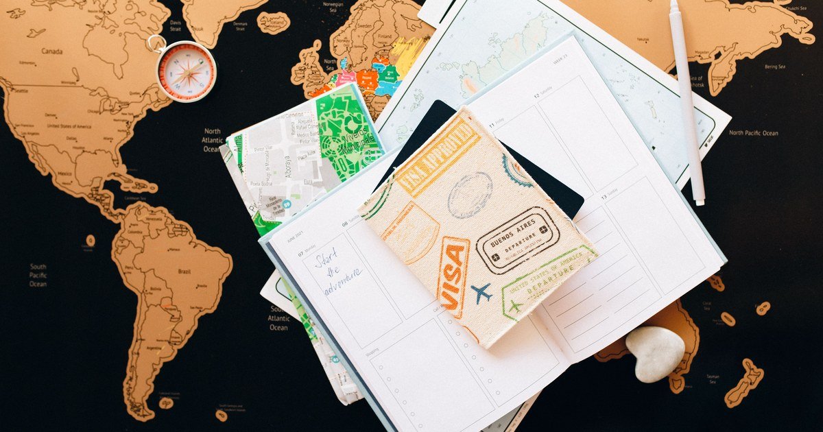 Hộ chiếu gắn dấu visa đặt trên sổ ghi chú và bản đồ thế giới