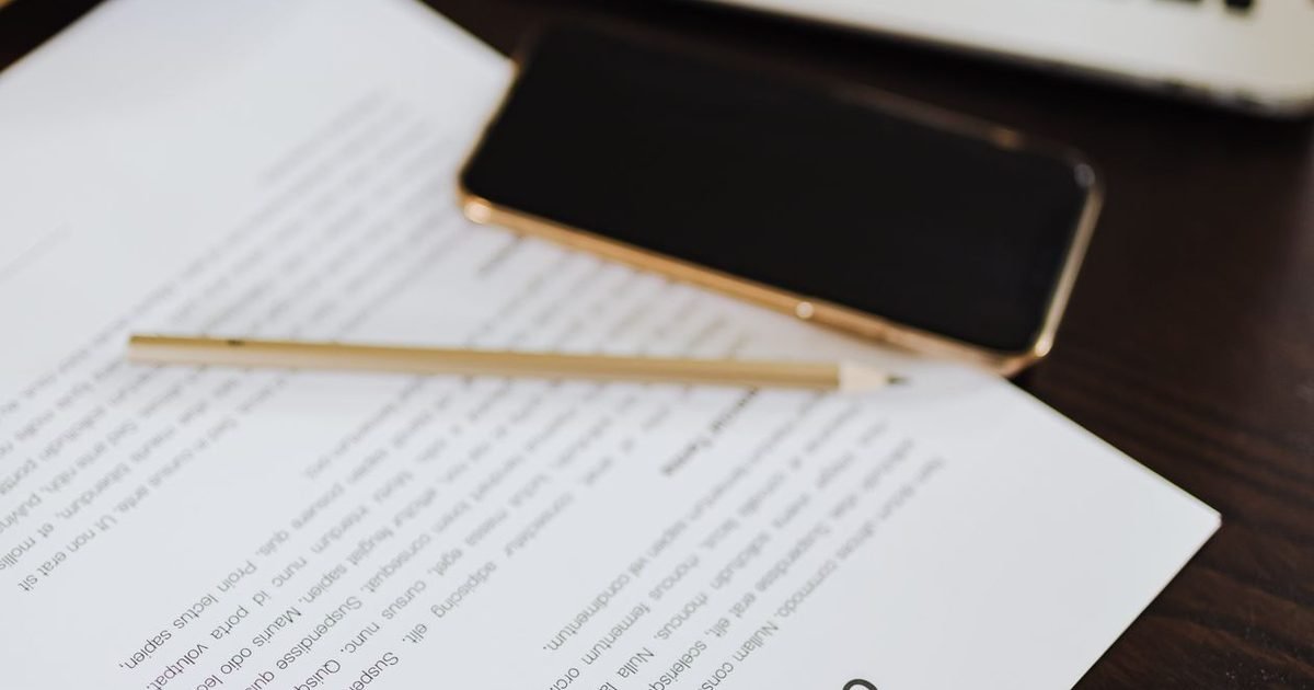 E-Contracts Under the New Law: Validity and Notes 1 Hợp đồng đặt trên bàn làm việc cùng điện thoại, bút và laptop, không người trong khung hình.