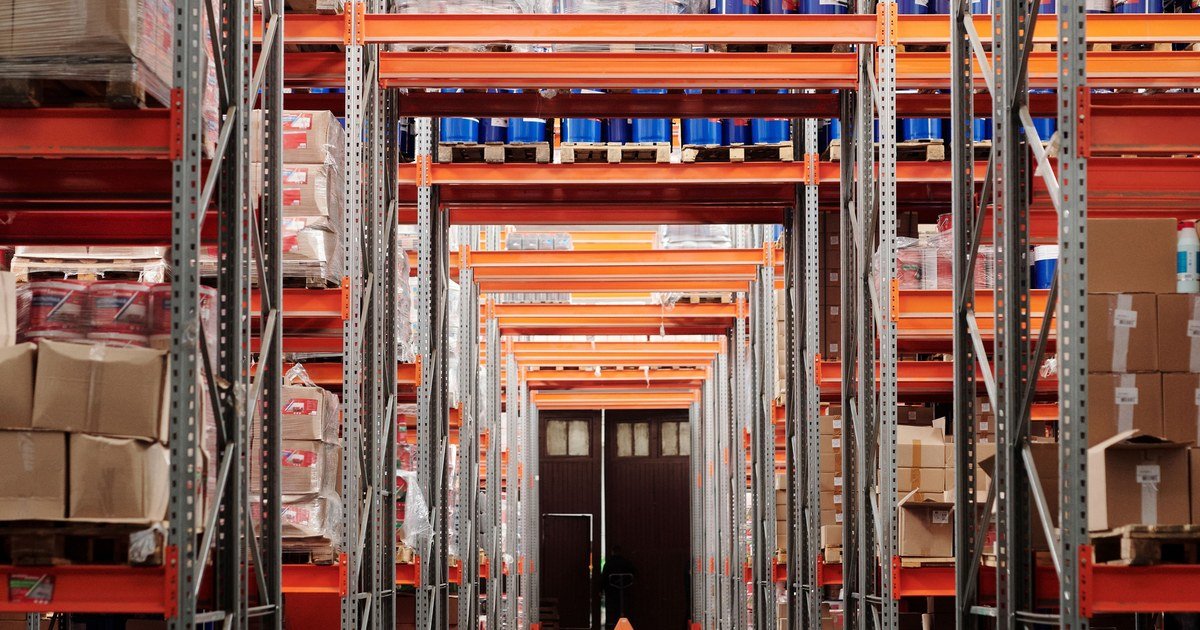 Nhà cung cấp tự ý đổi tiêu chuẩn hàng: xử lý 2026 1 Dãy kệ kho hàng chất đầy thùng carton trong nhà kho