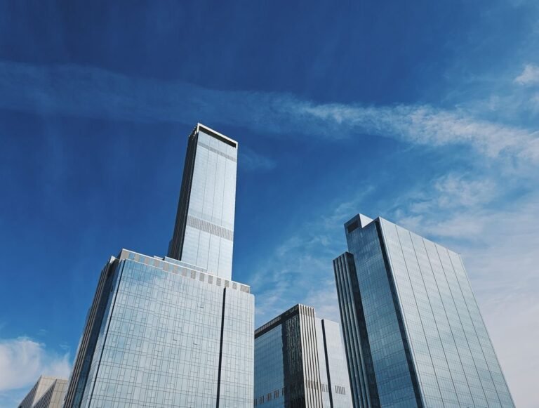 A cluster of glass headquarter towers under a blue sky — illustrating group audit