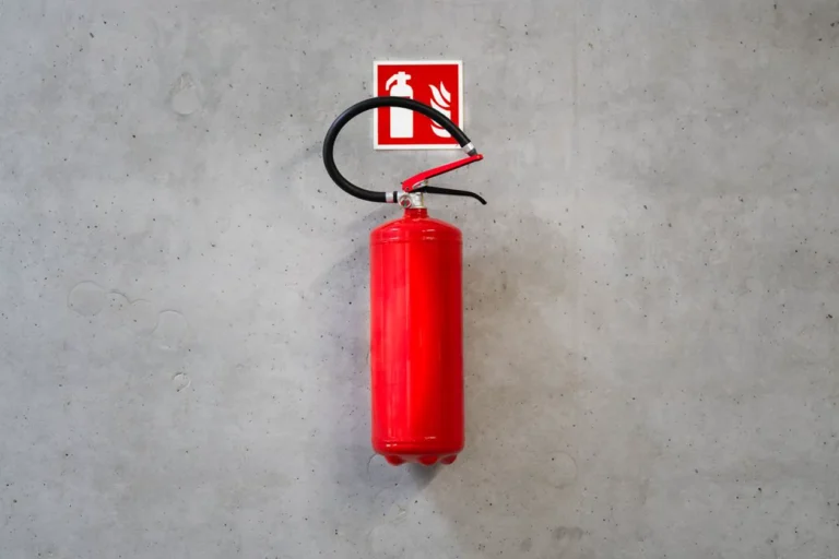 Red fire extinguisher mounted on concrete wall