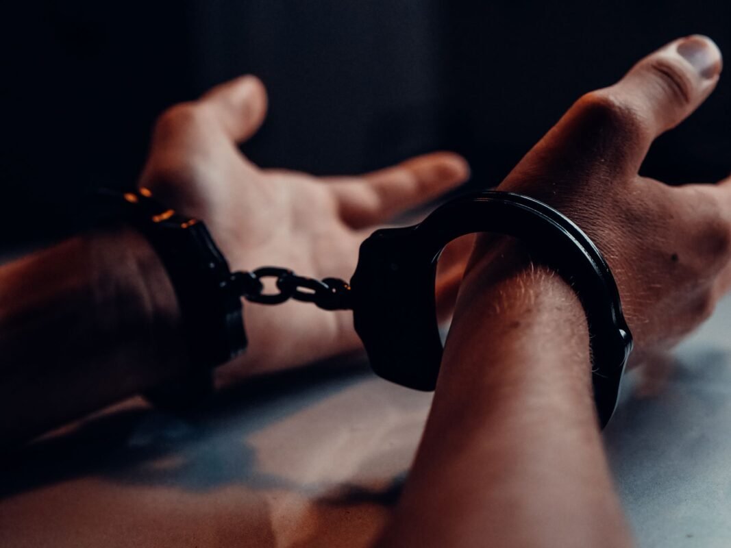 Hands in black handcuffs close-up — when administrative violations escalate to criminal prosecution, no face