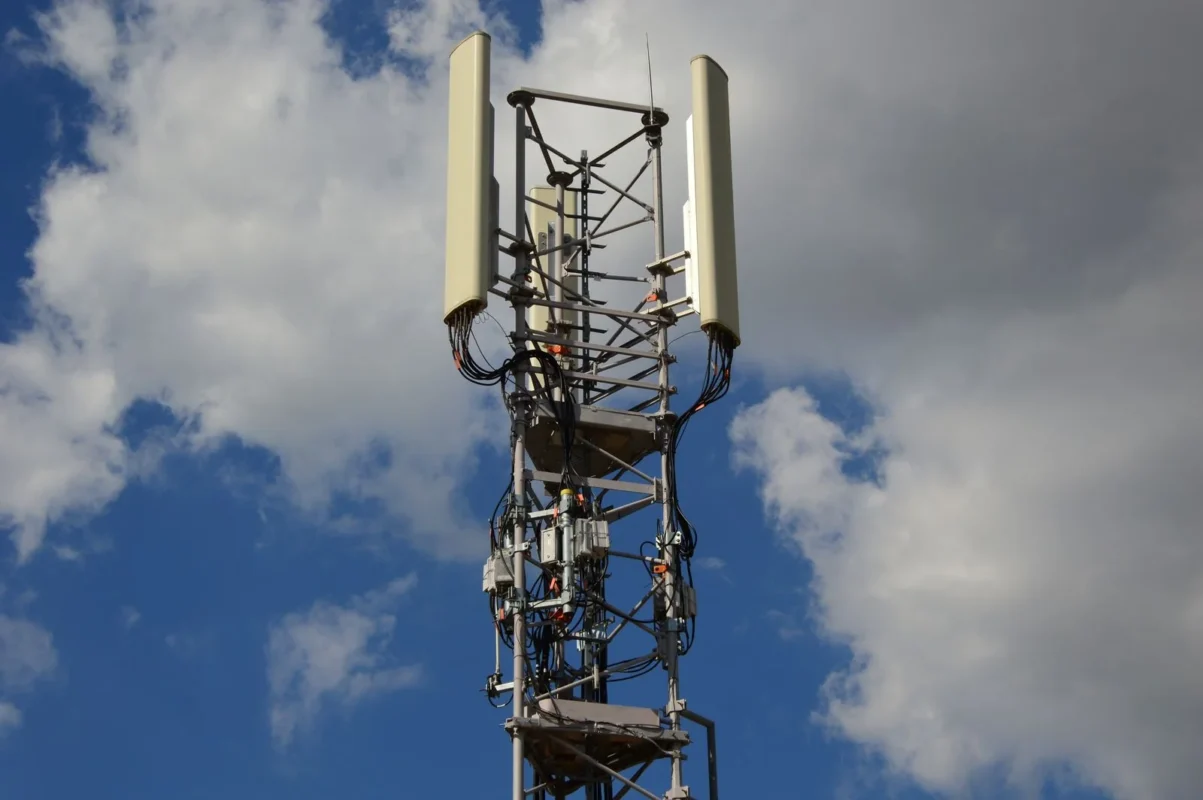Telecom service business licensing — tall cellular tower against a vivid blue sky