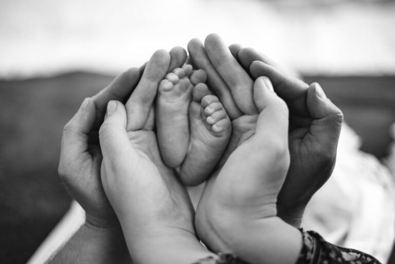 Adult hands cradling a newborn baby feet — illustrating 2026 maternity benefits