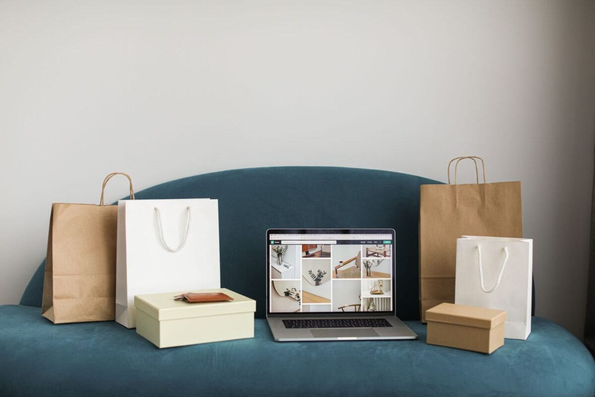 Máy tính xách tay và túi mua sắm trên ghế sofa — minh họa bài về thu thập dữ liệu khách hàng trên website thương mại điện tử, không có người