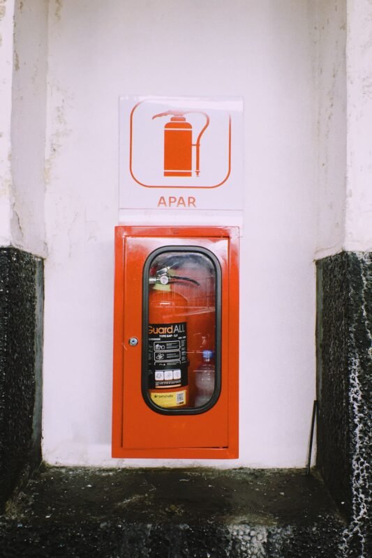 Wall-mounted red fire extinguisher with safety signage indoors