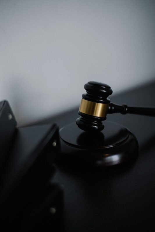 Black wooden gavel with golden strip on a table near stacks of folders