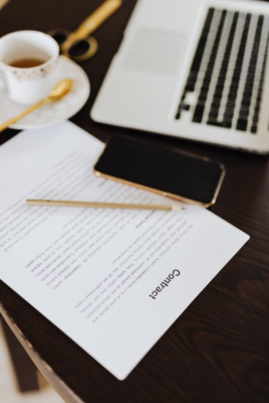 Contract, laptop and smartphone on a desk — illustrating patent licensing
