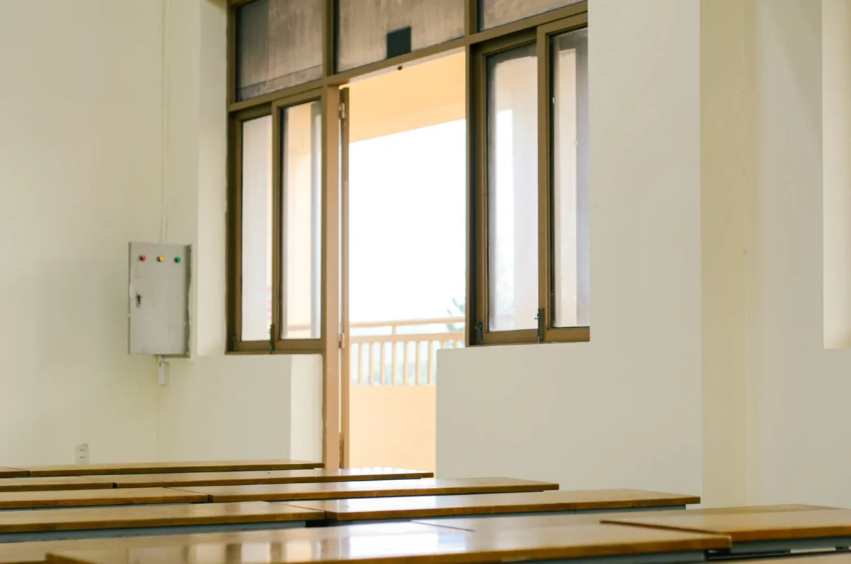 Sunlit empty classroom with wooden desks