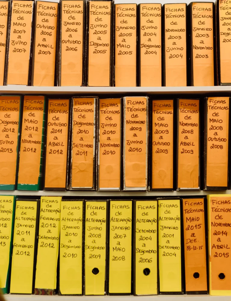 Rows of labeled binder folders on a shelf