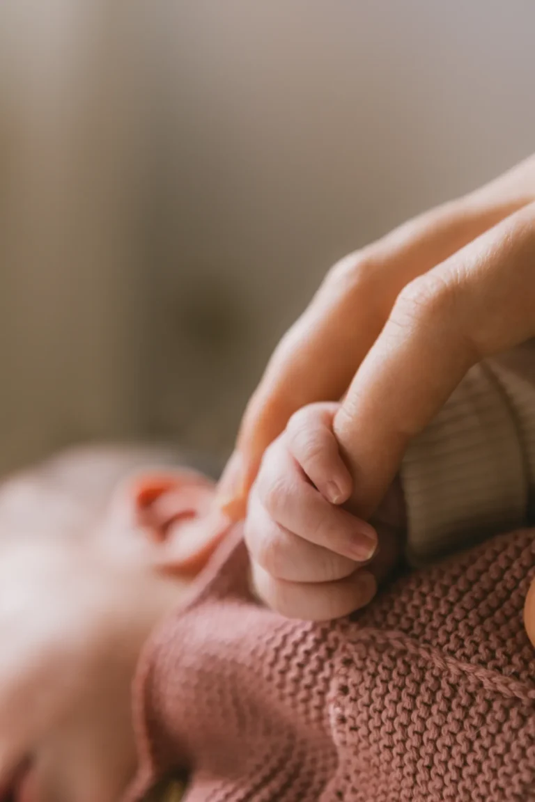 Bàn tay mẹ nắm tay em bé; không thấy mặt