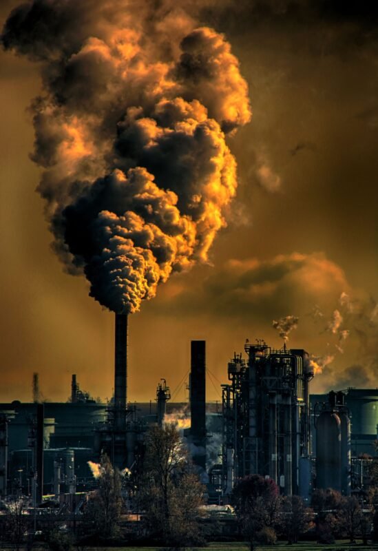 Industrial smokestacks emitting thick smoke — illustrating a factory director's criminal liability when the company pollutes the environment