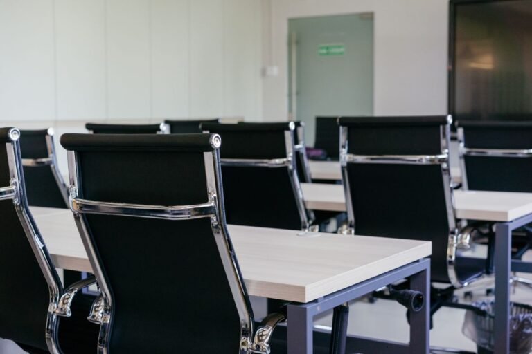 Empty modern conference room with black chairs and white desks