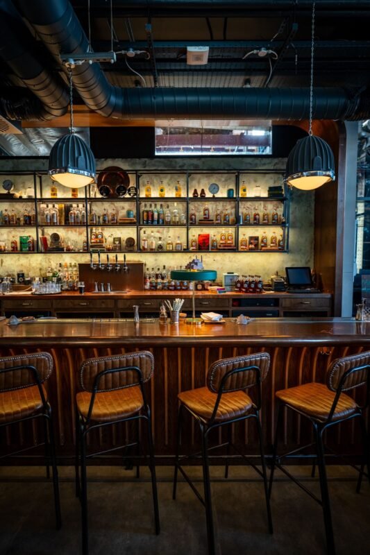 Quầy bar gỗ với kệ rượu, không người — minh họa điều kiện và hồ sơ xin giấy phép an ninh trật tự cho quán bar, pub