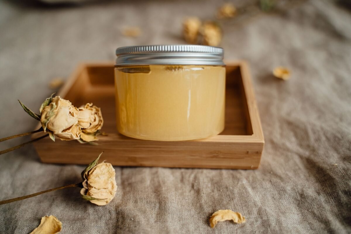 Cosmetic balm jar on a wooden tray with dried roses