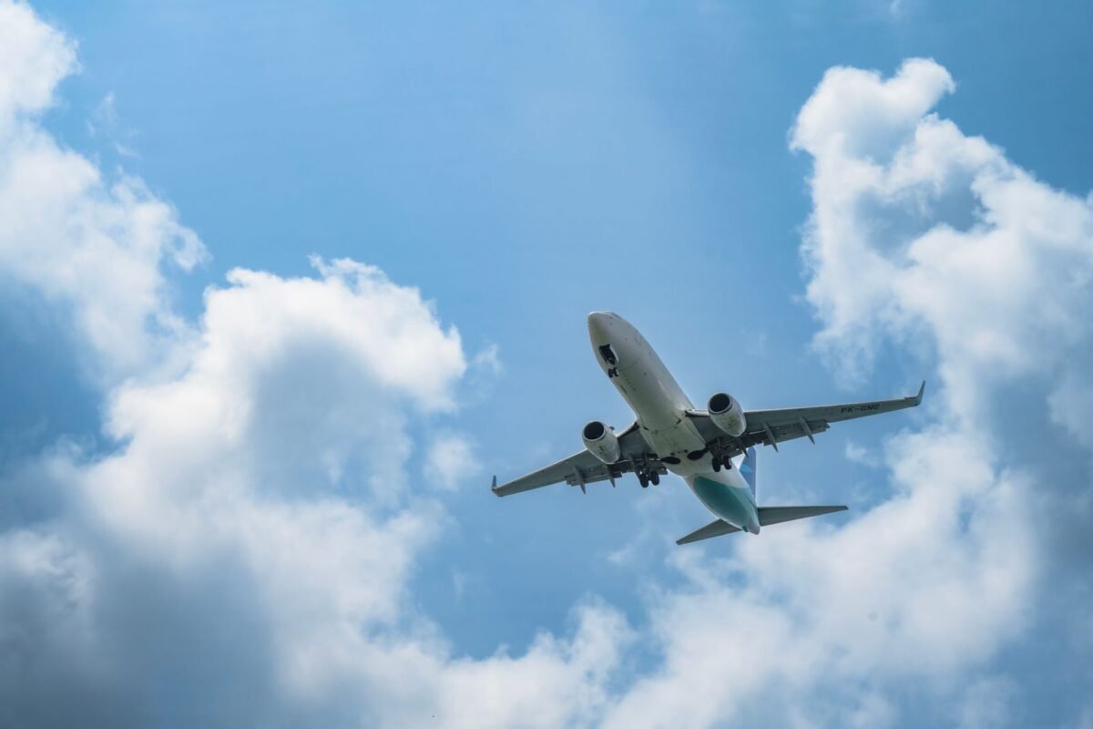 Commercial airplane flying through clear blue sky — entering Vietnam with under 6 months of passport validity