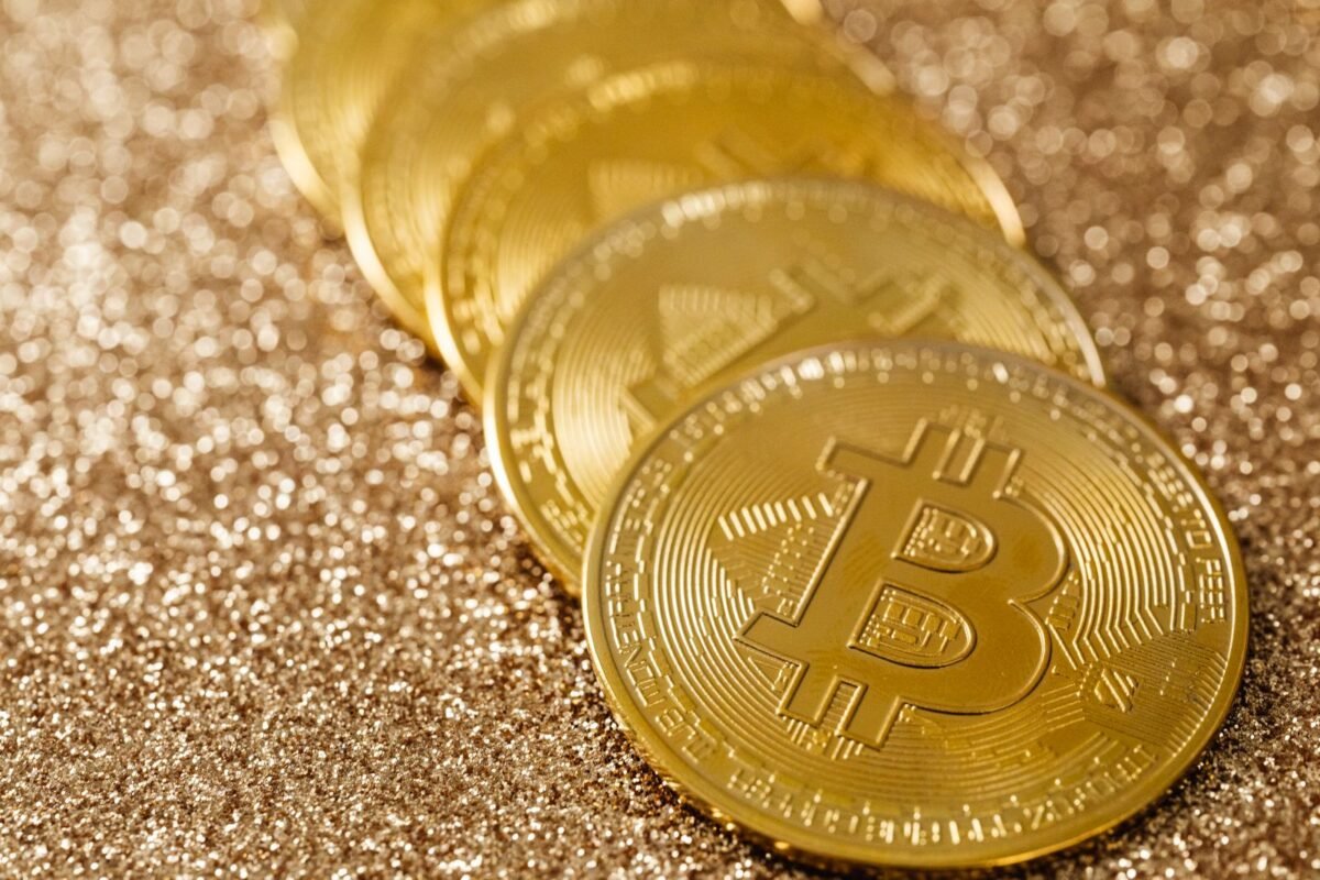 Close-up of golden Bitcoin coins on a shimmering glitter background, symbolizing digital currency's allure