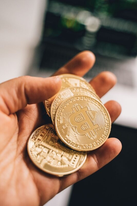 Close-up of a hand holding multiple Bitcoin coins symbolizing digital currency and economic growth