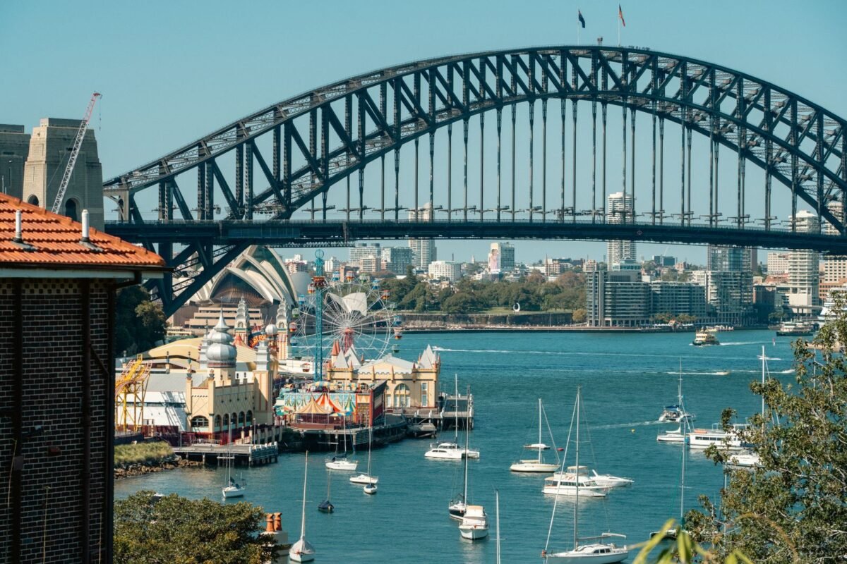 A vibrant view of Sydney Harbour Bridge with Luna Park and sailboats