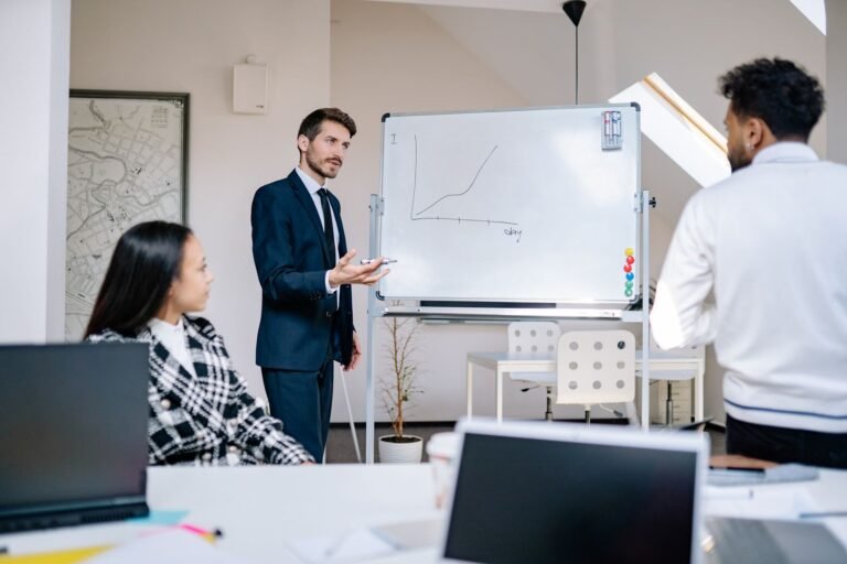 Business team in office presenting growth graph on a whiteboard for strategy discussion