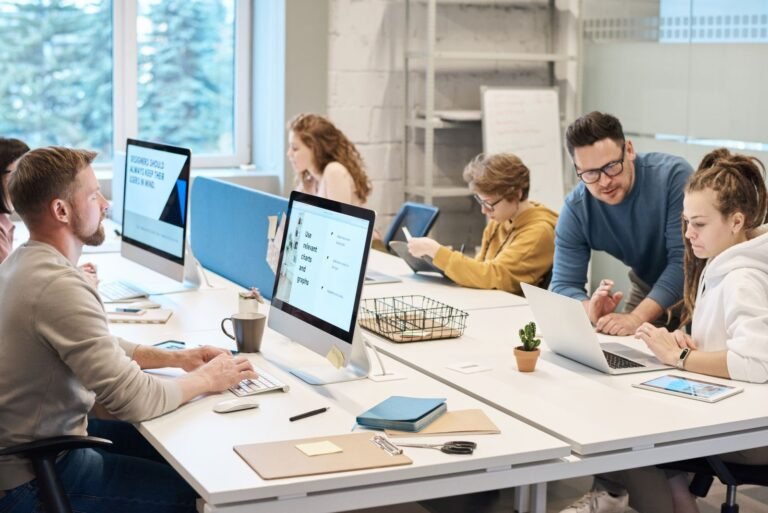 Team collaboration in a modern office setting with computers and diverse employees working together