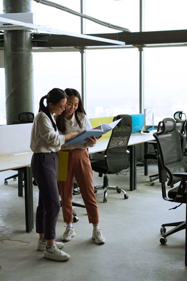 Two women reviewing documents in a spacious, well-lit modern office setting