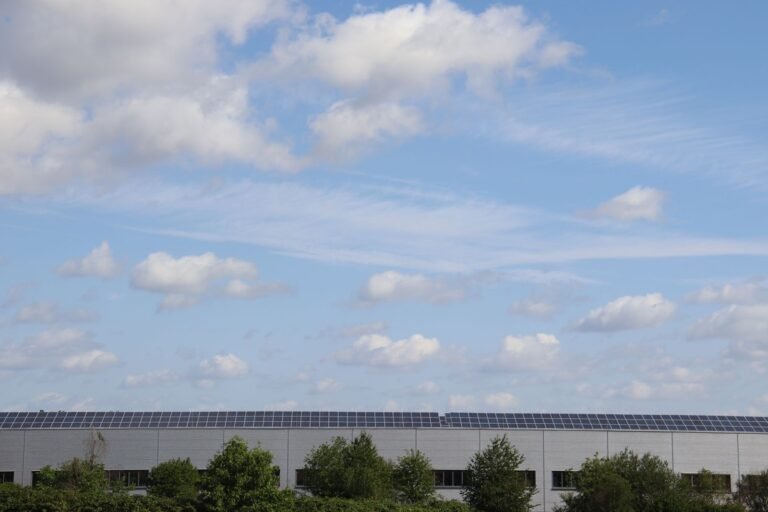 Warehouse roof adorned with solar panels beneath a bright blue sky