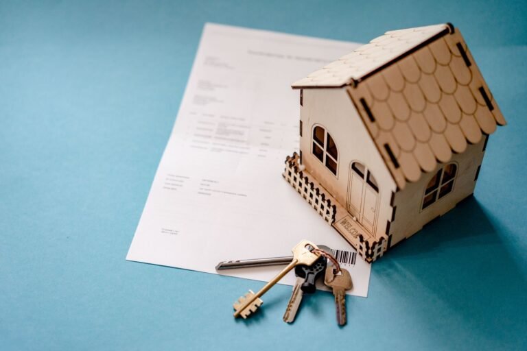 Miniature wooden house with keys and contract symbolizing real estate transactions