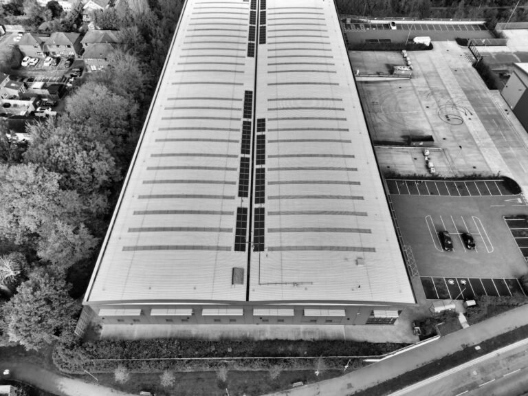 Black and white aerial view of a warehouse in Hertfordshire with solar panels and parking area