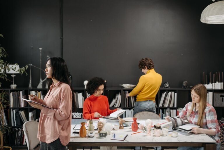 A group of adults engaged in creative work and discussion around a table in an office setting