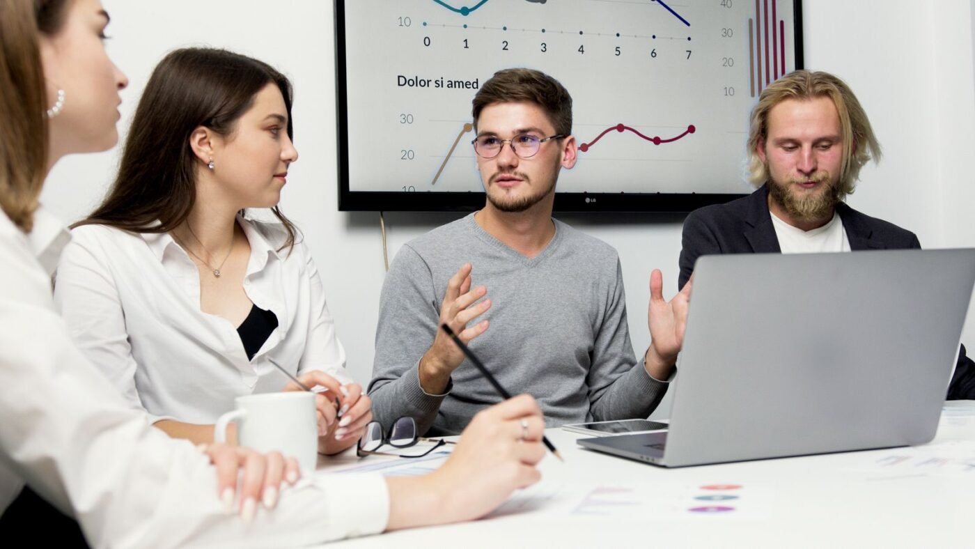 Group of colleagues discussing strategy with charts in the background