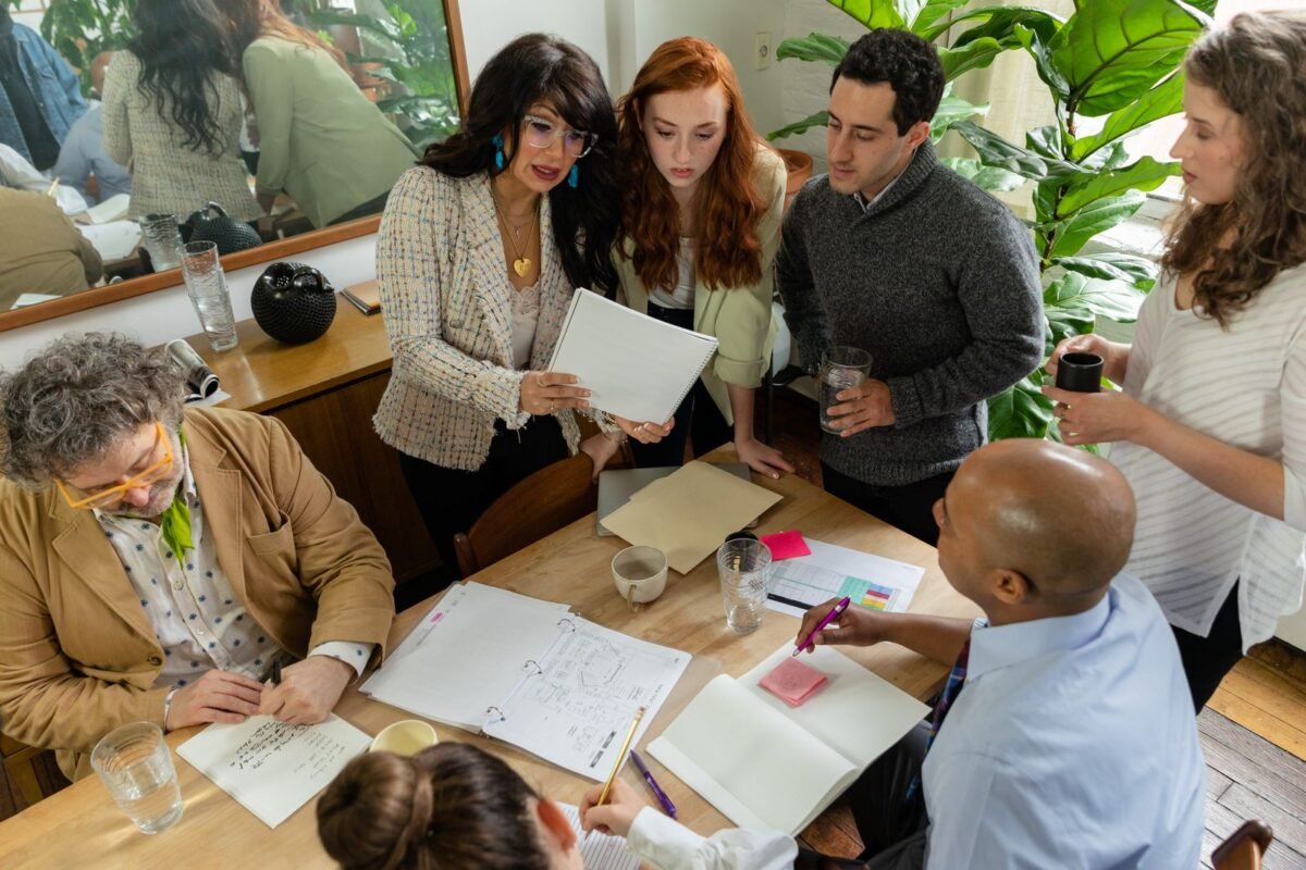 A diverse team discusses documents around a table in a modern office setting, promoting teamwork and collaboration