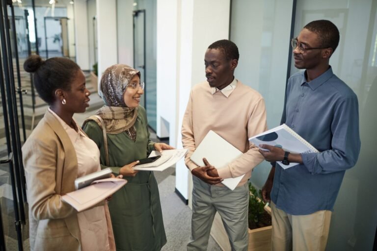 A group of multicultural colleagues discussing work materials in a modern office setting