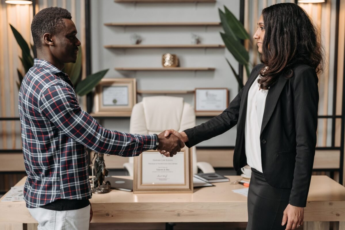 Two professionals shaking hands in an office, symbolizing a successful business agreement