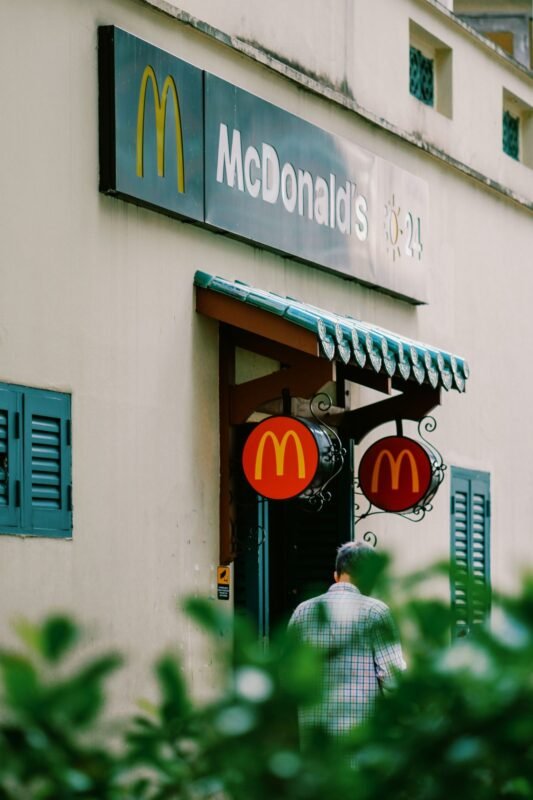 A person entering a McDonald's in a city setting, showing branded signage and entrance decor