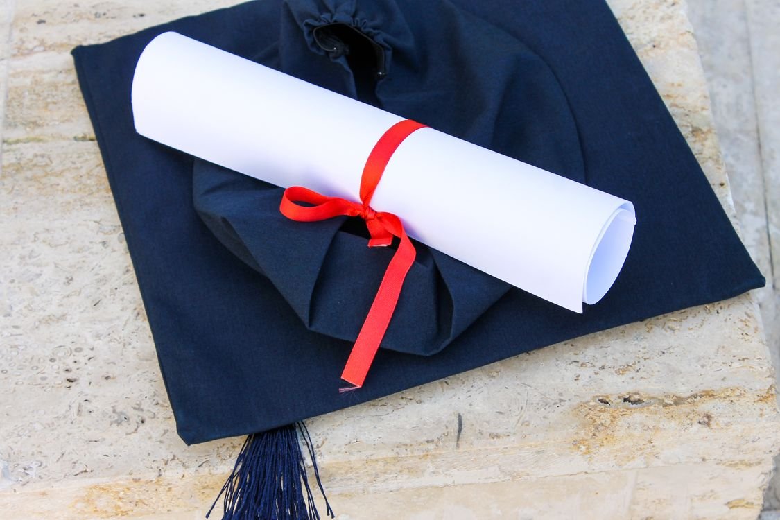 混血和外籍孩子在越南的奖学金 1 Graduation cap with diploma roll tied with red ribbon on concrete surface