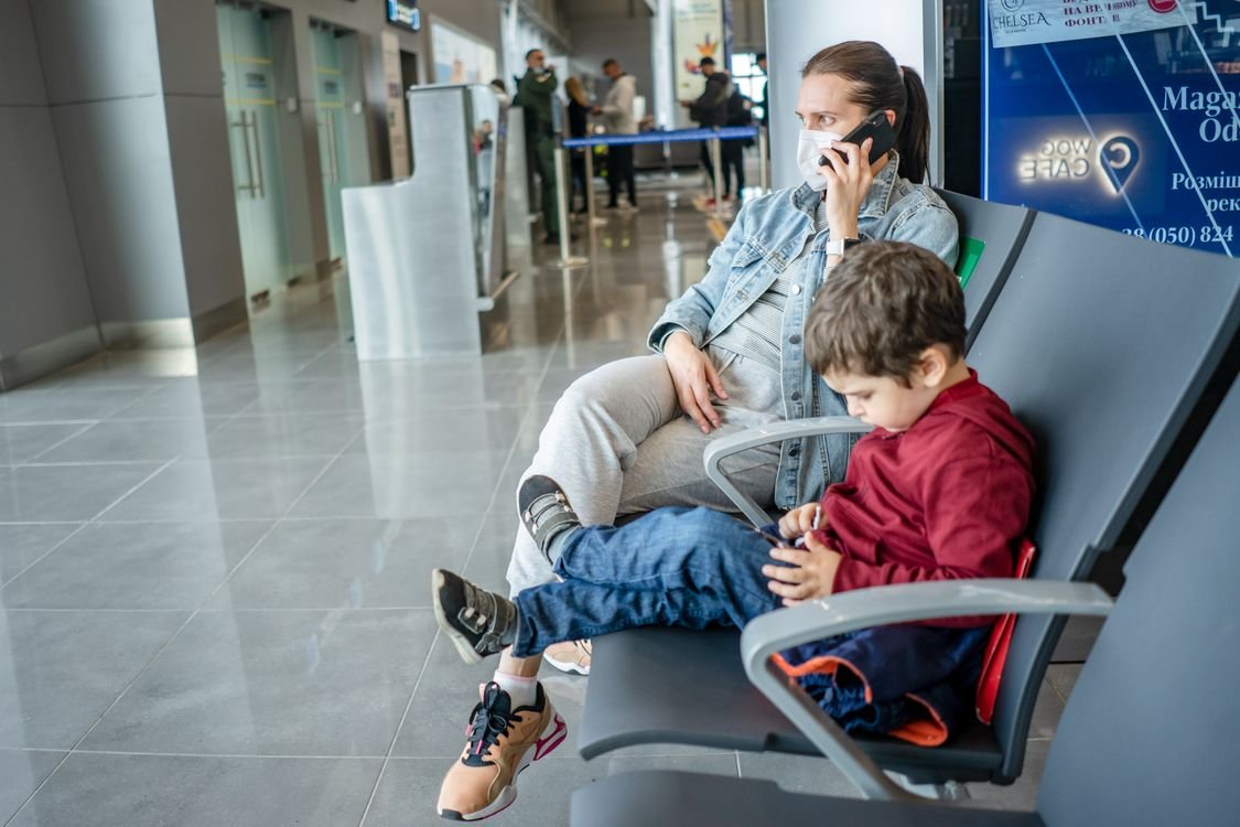 A mother and child sitting at an airport terminal
