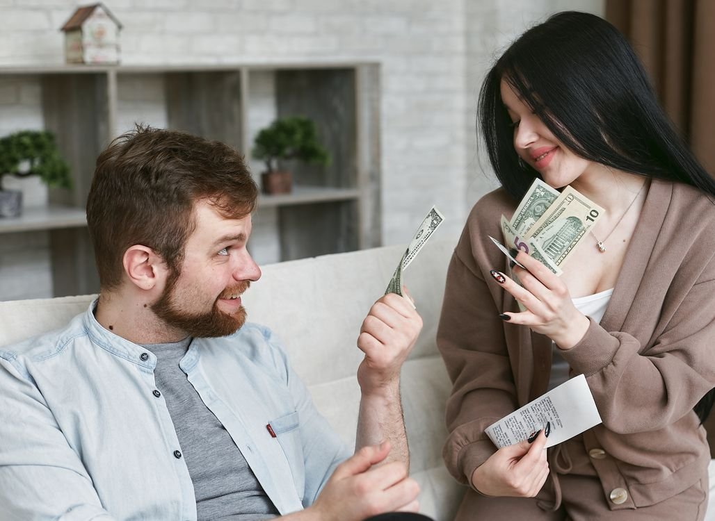 Couple managing household finances with cash and receipts at home