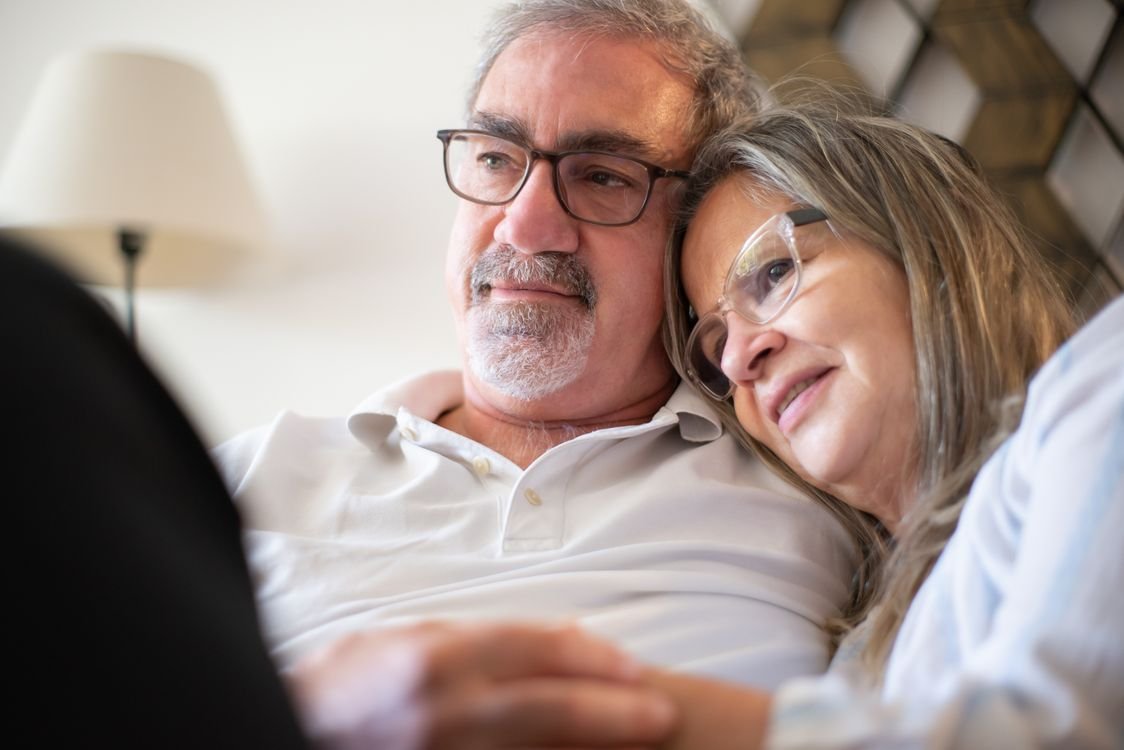 A loving elderly couple embracing and smiling indoors