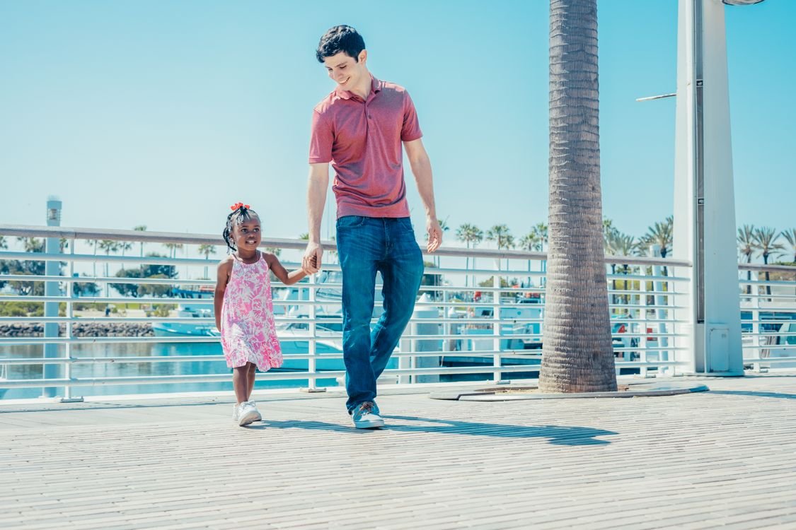 未成年继承人的监护:谁管理孩子的财产? 1 A dad and daughter enjoy a sunny walk by the marina holding hands