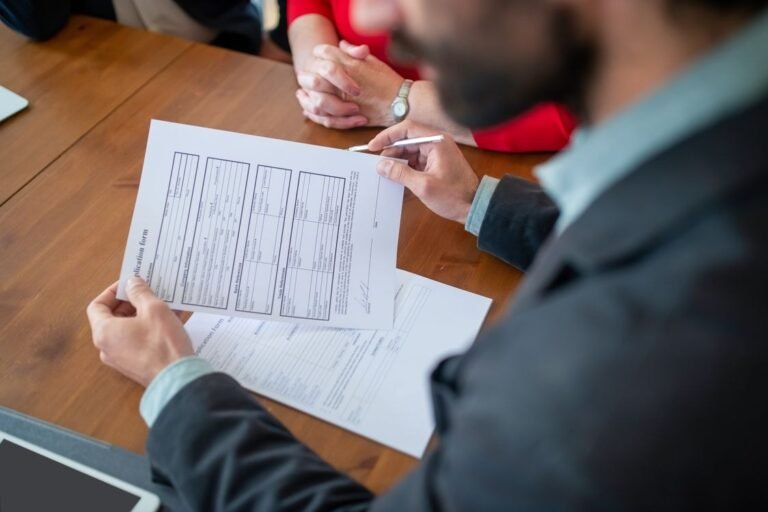 Person Holding a Document on a Wooden Table