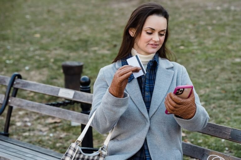 Glad woman making online payment via smartphone in spring park