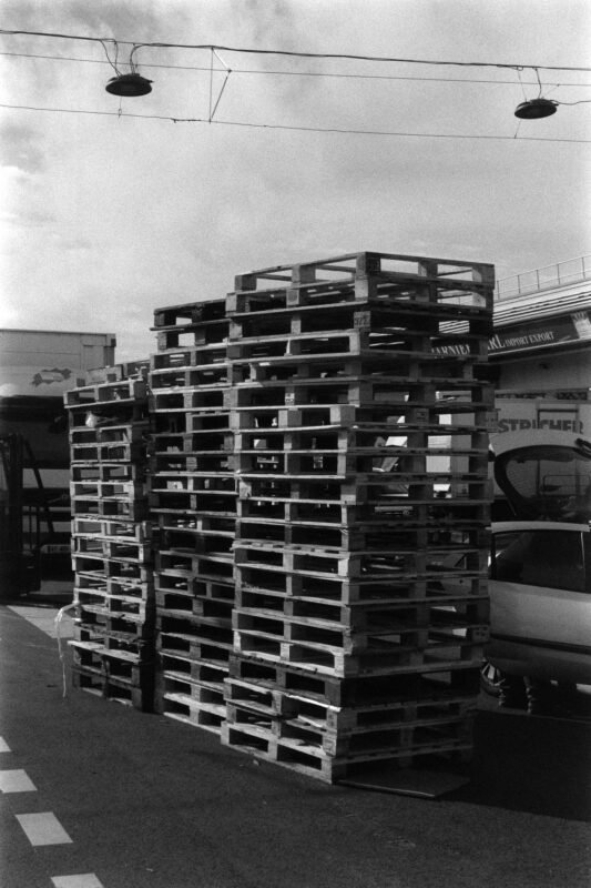 Duty-free import of raw materials for manufacturing export goods — stacked wooden pallets in industrial storage area, no people