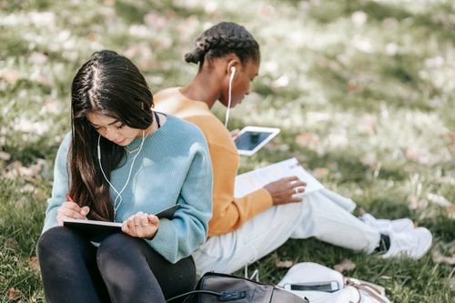 Student taking notes with a tablet in a park — illustrating interns and apprentices rights and contracts