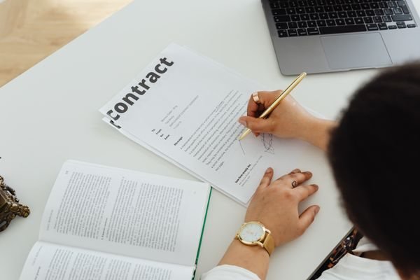 Person signing a contract at a desk (illustrative)