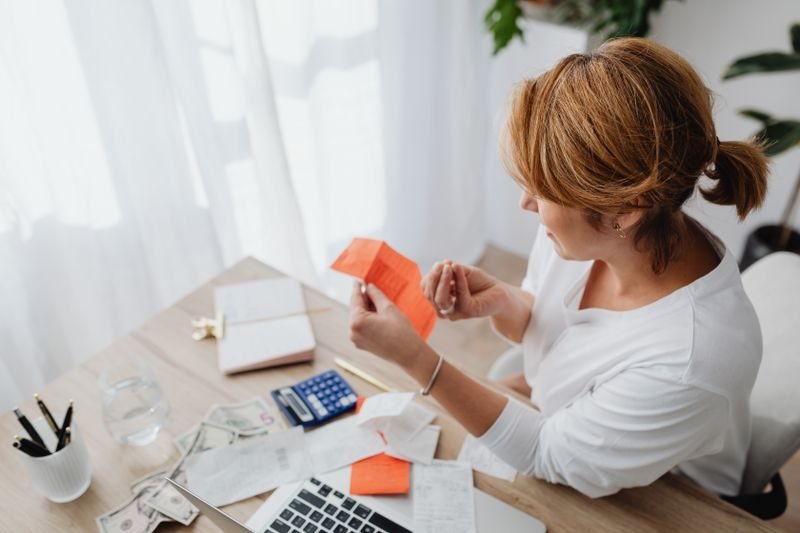 Người phụ nữ tính toán với máy tính tại bàn làm việc